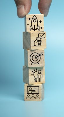 Businessman puts a wooden block of business symbols. Marketing and product planning ideas, startups, product manufacturing orientations.